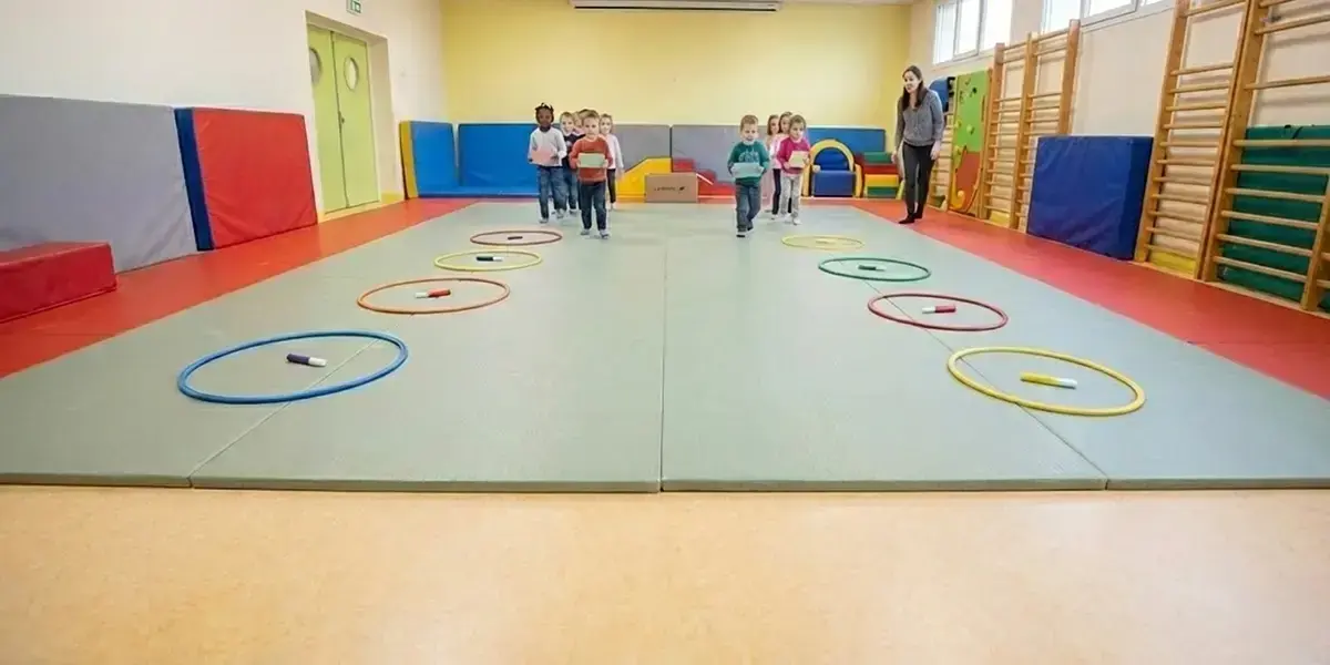 Enfants jouant au jeu du Facteur des Cerceaux en maternelle : course de relais pour livrer le courrier dans les cerceaux depuis la boîte située au fond de la salle